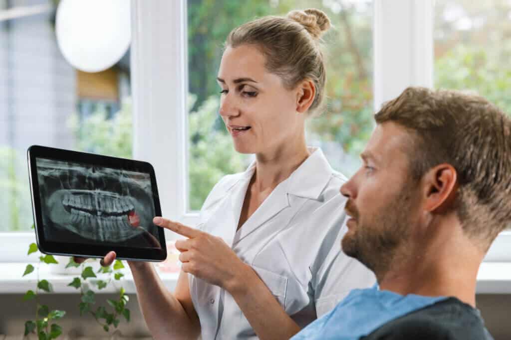 dentist showing and explaining dental x ray picture with impacted wisdom tooth to his patient