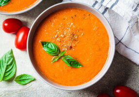 traditional gaspacho in gray bowl. summer tomato soup with basil