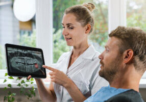 dentist showing and explaining dental x ray picture with impacted wisdom tooth to his patient